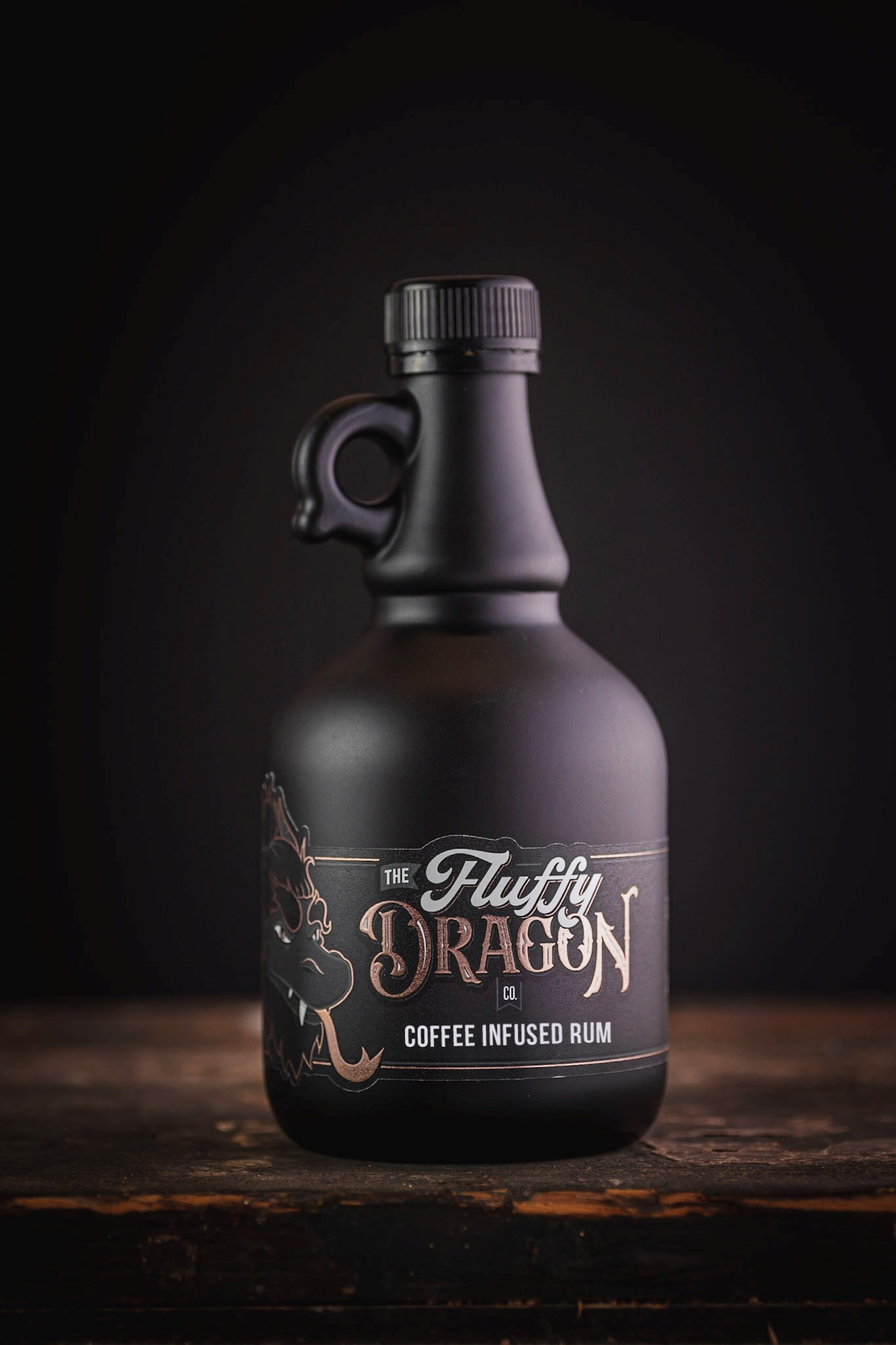 A photo of The Fluffy Dragon Co black bottle on a wooden table with the coffee infused rum label